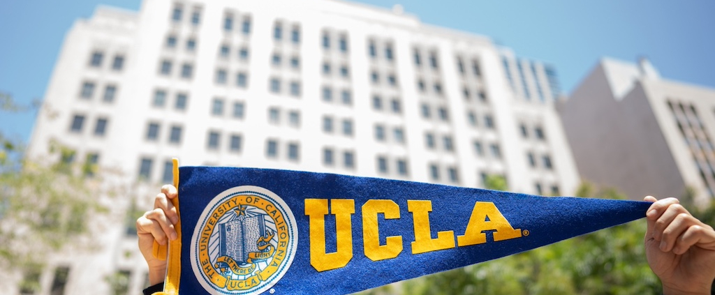 An individual hols up a UCLA pennant.