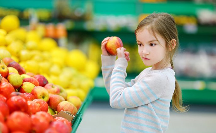 Little girl choosing an apple in a food store