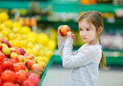 Little girl choosing an apple in a food store