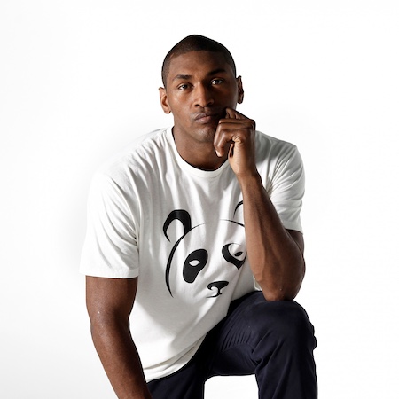 A young man wearing a white panda shirt kneels with his arm propped on his knee and holding his face with a contemplative expression.