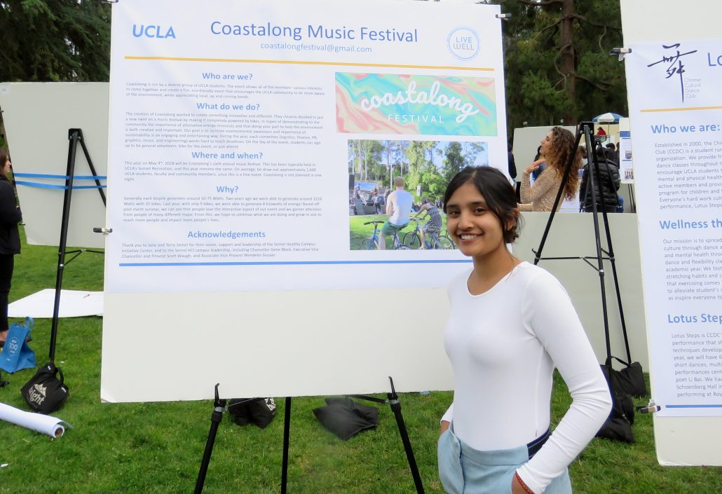 A student stands in front of their poster, Cooastalong Music Festival at a research fair.