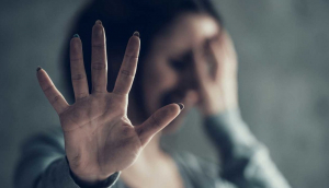 A woman holding her hand up to block camera.