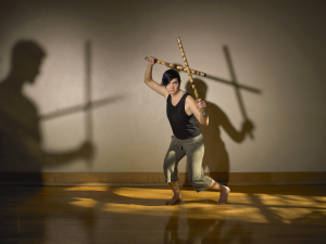 A woman practices martial arts with sticks