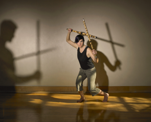 A woman practices martial arts with sticks