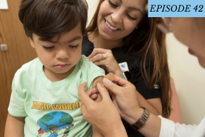 Episode 42 featured image: A young boy gets a bandage on his arm with a young woman holding him with a bright smile