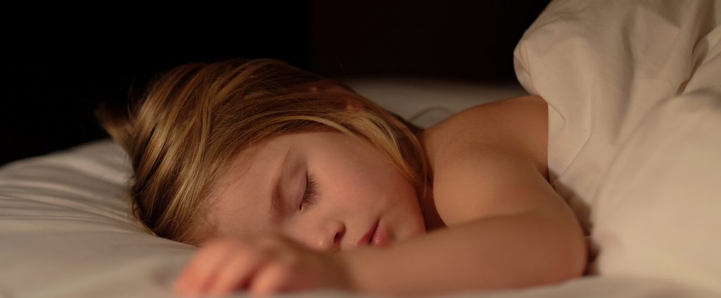 A young child sleeps in her bed.