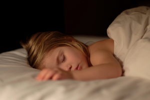 A young child sleeps in her bed.
