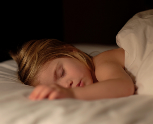 A young child sleeps in her bed.