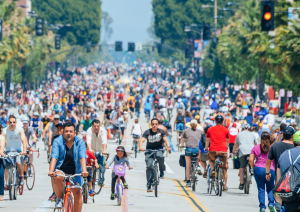 A 2-way street is almost completely filled with a large quantity of bikers riding up and down the street.