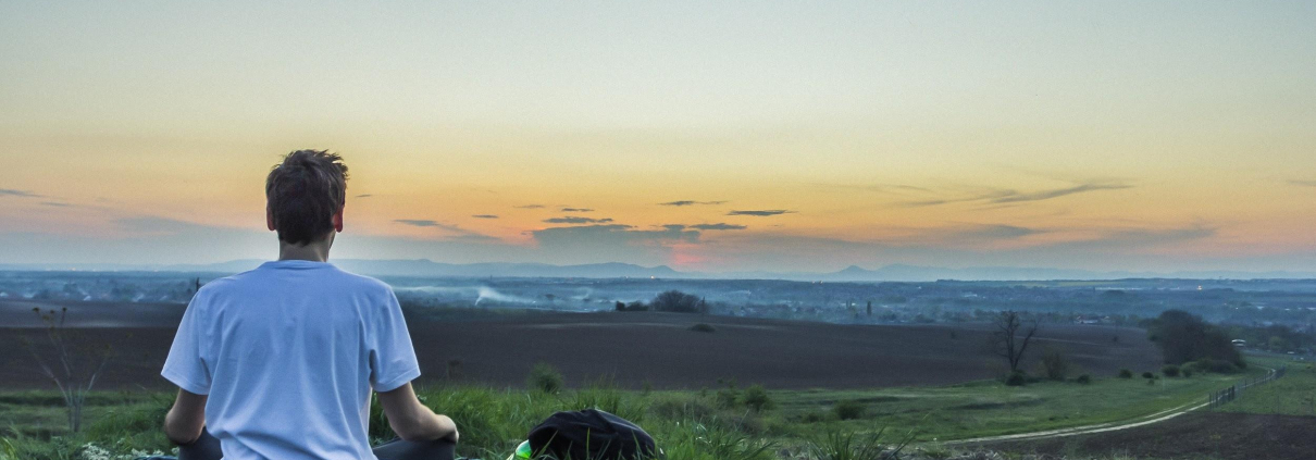 man meditating on a field