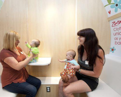 Women hold their babies while conversing with one another.