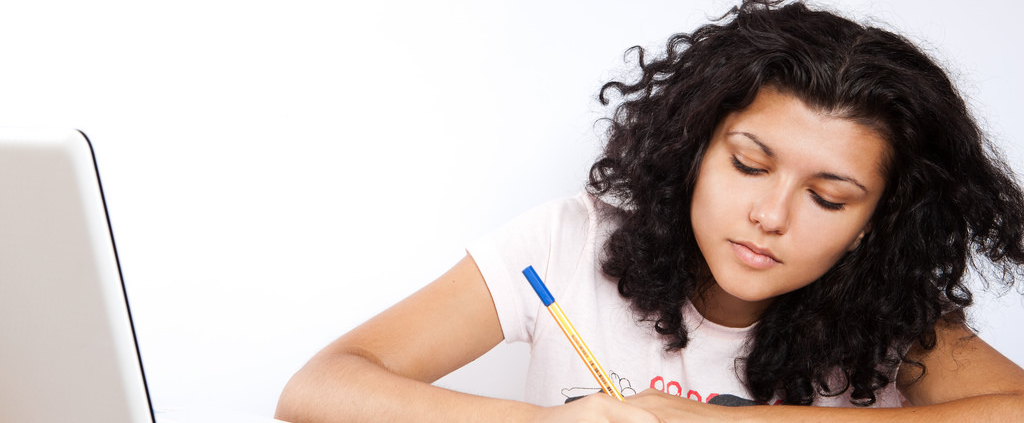 A student studies on a notebook next to her laptop.