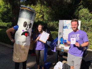 2 people standing in front of a board promotes the fight for lunch cancer with a cigarette mascot.