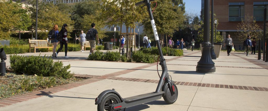 Bird scooter is placed in the middle of the walkway.