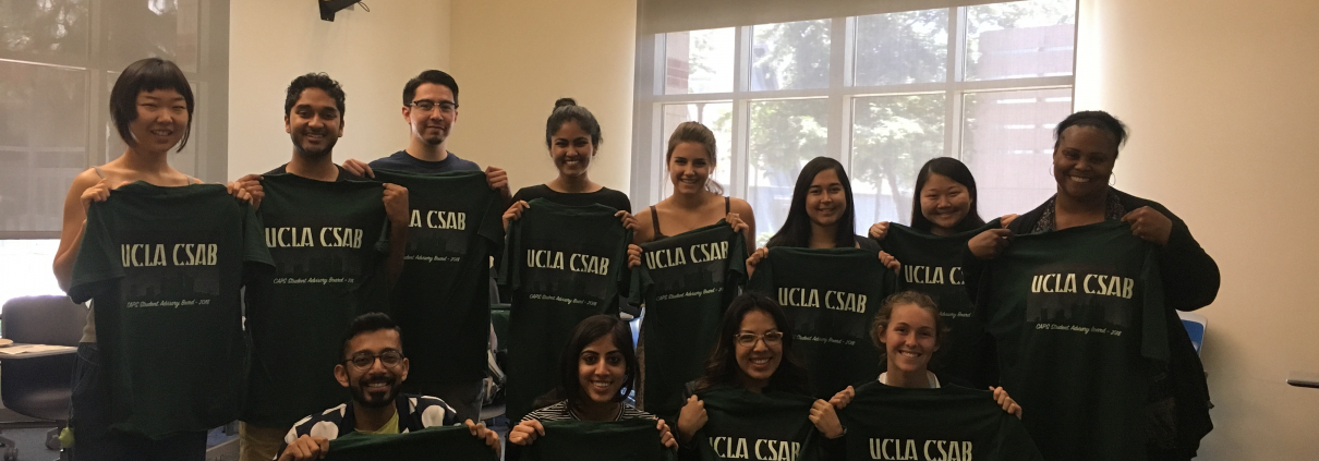 A group of individuals hold up UCLA CSAB t-shirts.