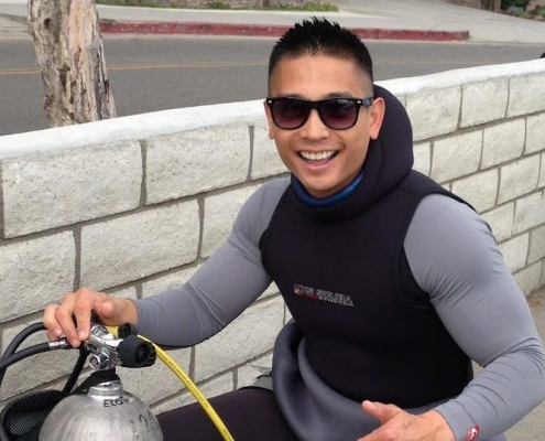 A man poses next to a gas tank with a large smile.