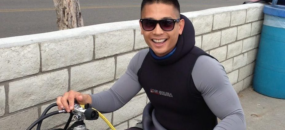 A man poses next to a gas tank with a large smile.
