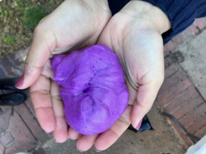 A student holds purple slime in their hands.