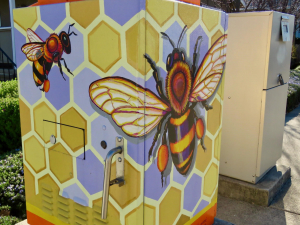 Bees are painted on utility boxes.