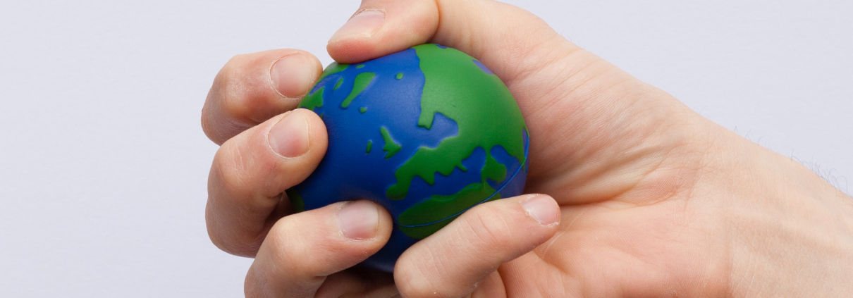 An individual squeezes an Earth shaped/designed stress ball.