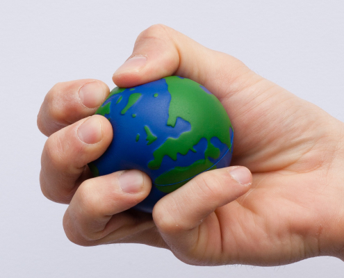 An individual squeezes an Earth shaped/designed stress ball.
