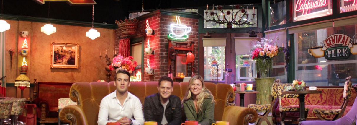 3 individuals sit on a couch in the middle of a dinner.