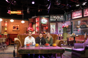 3 individuals sit on a couch in the middle of a dinner.