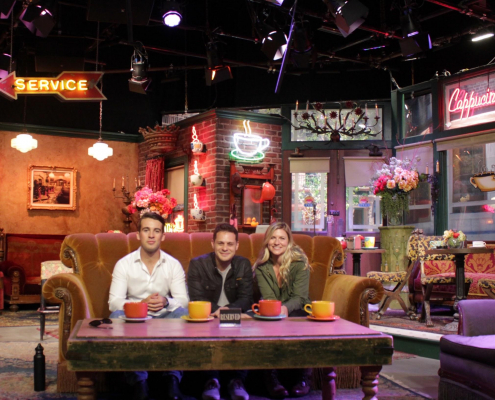 3 individuals sit on a couch in the middle of a dinner.