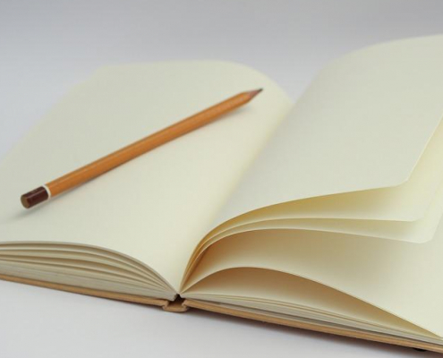 An open, empty notebook with a pencil placed in the middle.