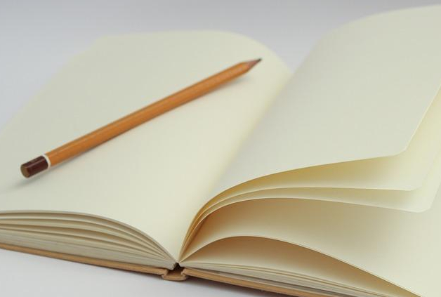 An open, empty notebook with a pencil placed in the middle.