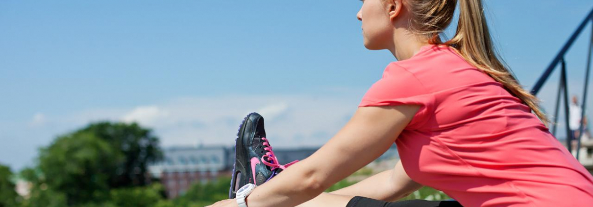 A woman stretches her foot on the railing.