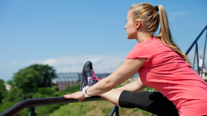 A woman stretches her foot on the railing.