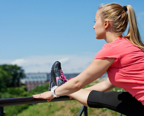 A woman stretches her foot on the railing.