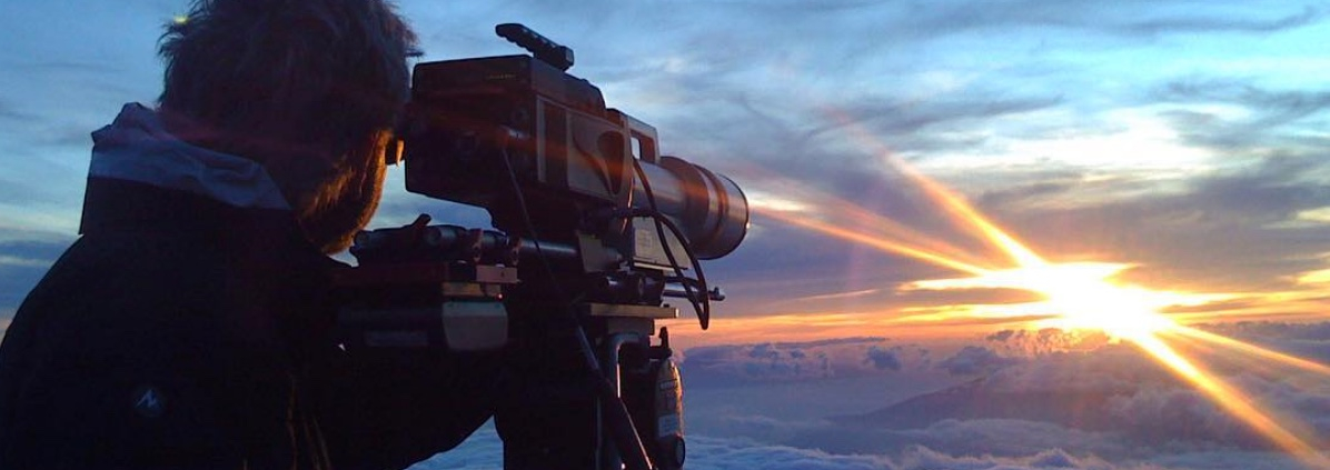 A filmmaker takes a video of a beautiful sunset over the clouds.