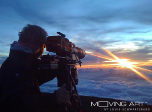 A filmmaker takes a video of a beautiful sunset over the clouds.
