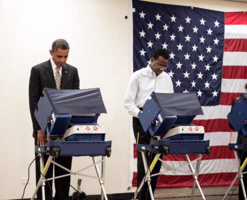 Barack Obama and other individuals vote at the in-person voting machines.