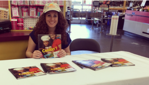 A woman holding a 'Kids get Cookin'!' book.
