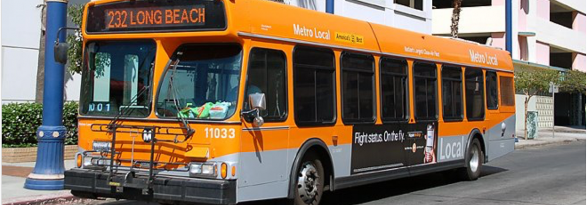 An orange bus is parked on the side of a road.