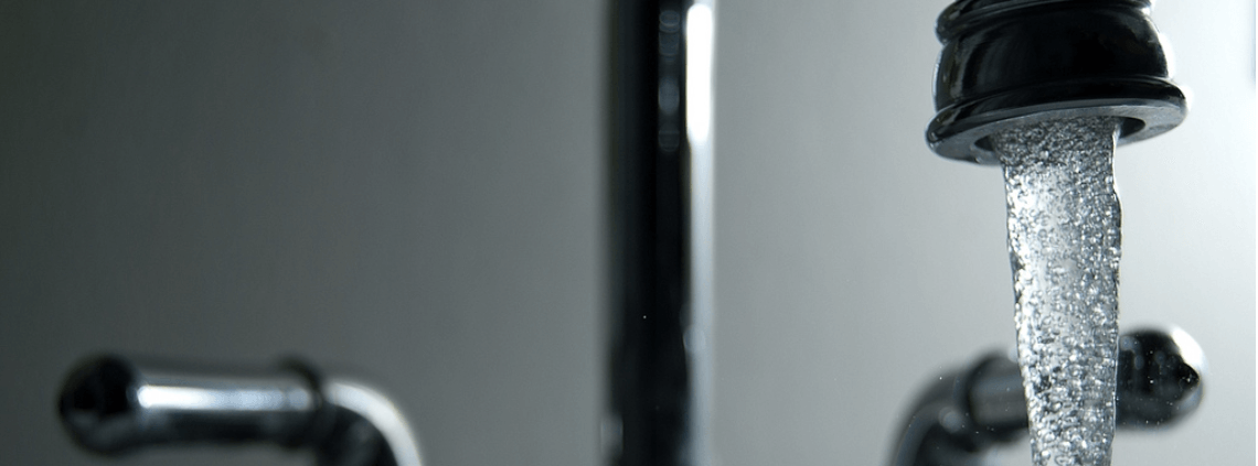 A close-up of a water faucet turned on.