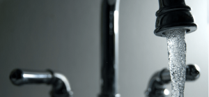 A close-up of a water faucet turned on.