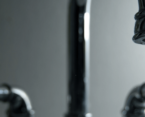 A close-up of a water faucet turned on.