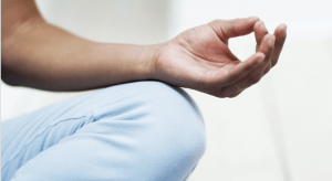 An individual holds up a yoga pose and holds their thumb and middle finger together.