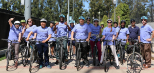 A group of individuals stand next to their bikes with helmets on, wearing Law Public Health t-shirts.