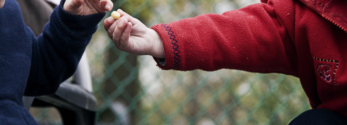 A child hands a candy to another child.