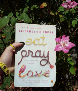 A person holds a book, 'Eat, Pray, Love.'