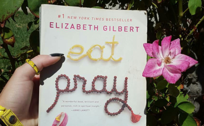 A person holds a book, 'Eat, Pray, Love.'
