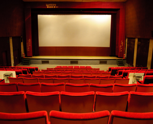 A lit-up empty theater filled with brilliant red seats and gold accents.