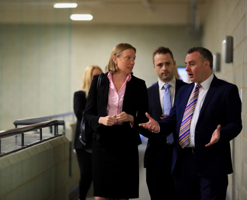 A professionally dressed group of individuals have a conversation with one another while walking.