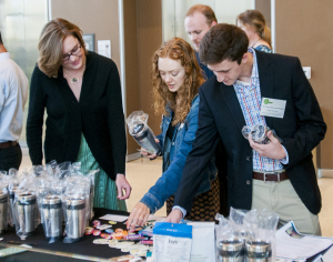 Multiple individuals grabbing snacks and other amenities from a table.